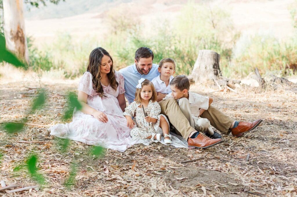 a family siting on a blanket in a field.