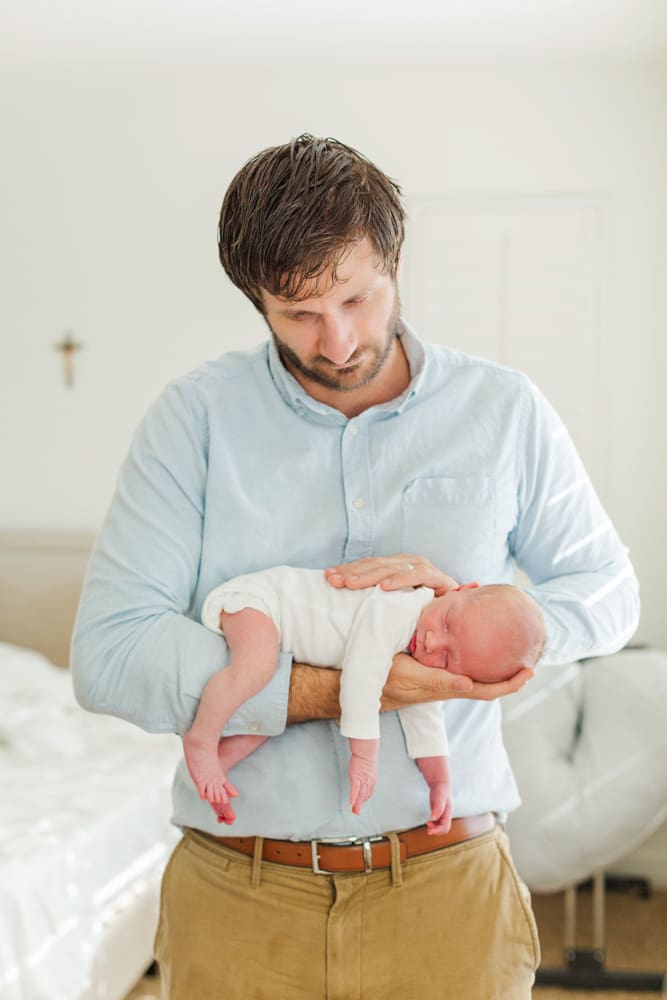 father in light blue shirt holding his newborn baby.