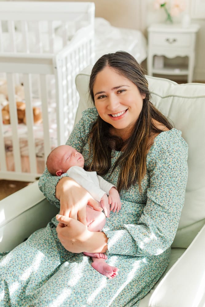 mother smiling at the camera while holding her newborn baby.