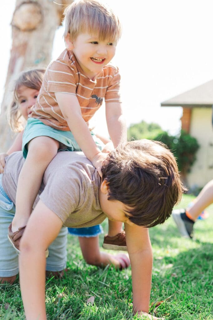 older boy is giving a younger boy a ride on his back.