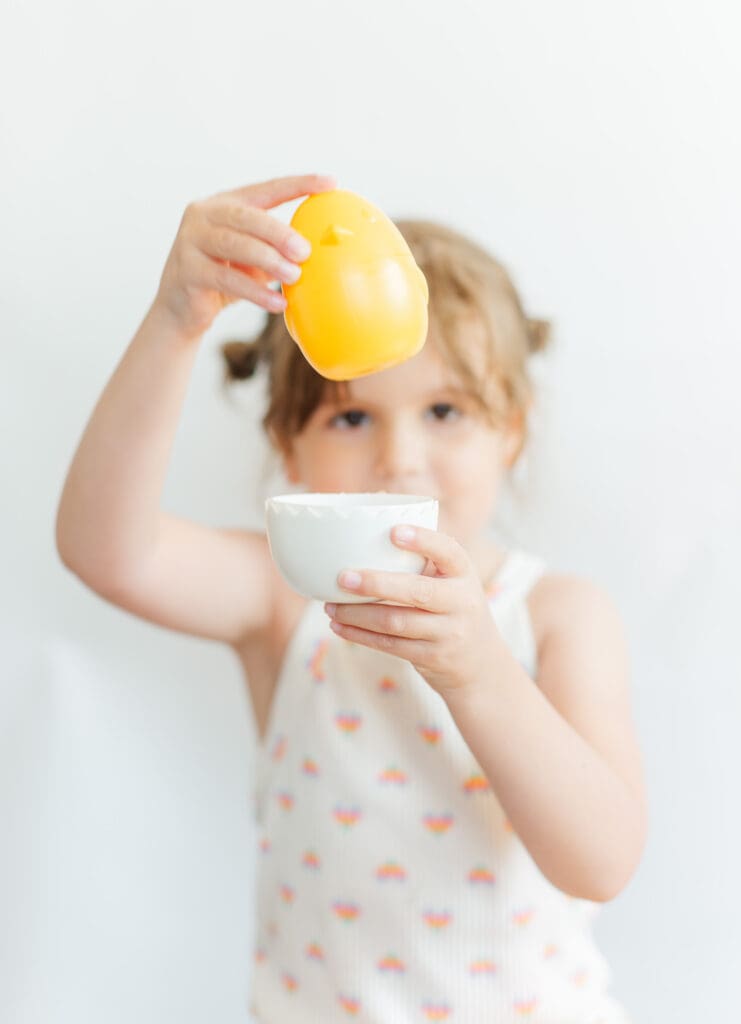 portrait of a girl holding up a toy egg and chick