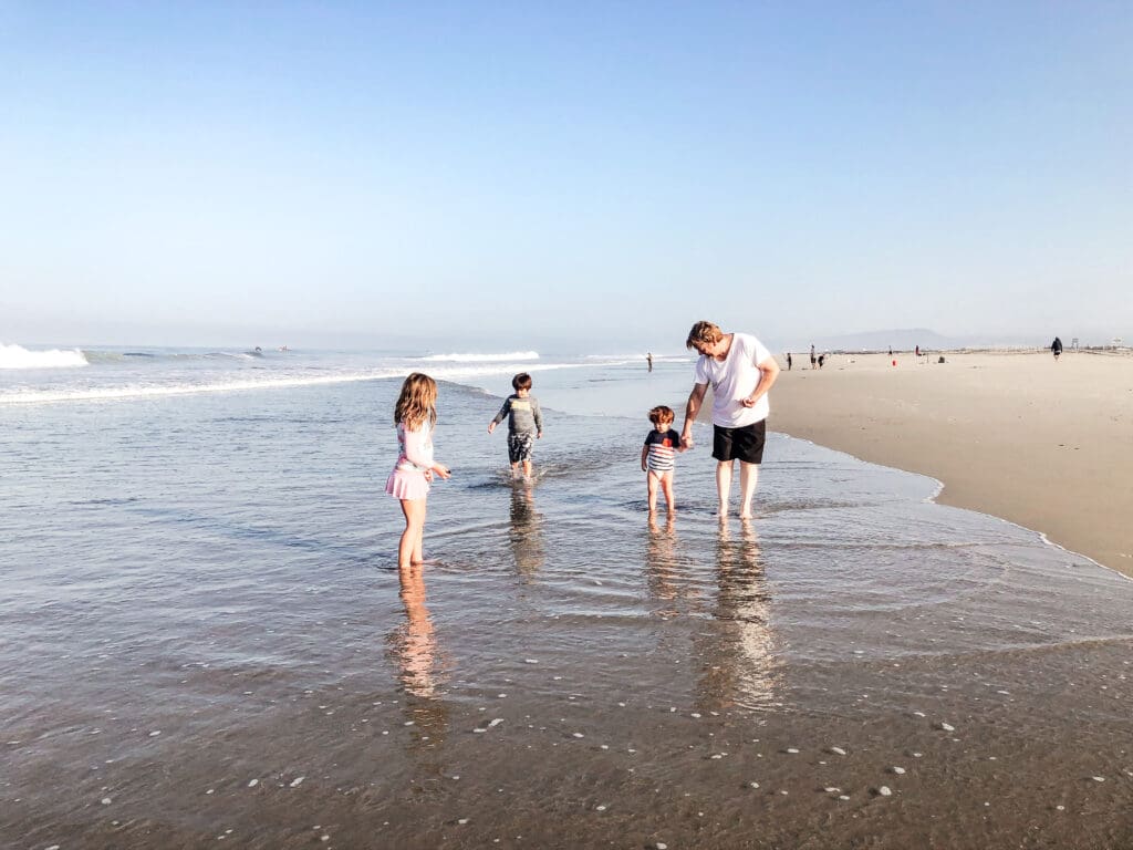 Dad with his little children walking on the beach in the early morning.
