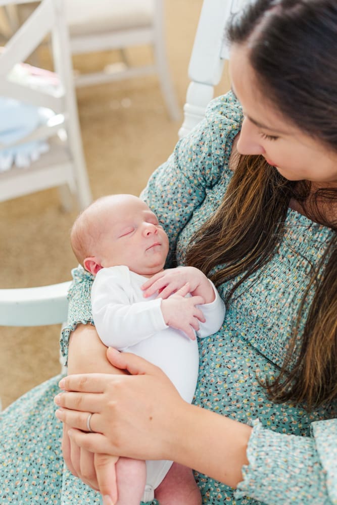 Temecula mom holding newborn while sitting down in a chair.