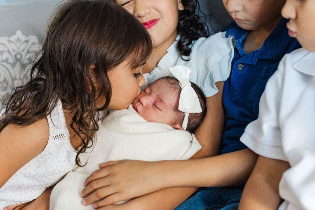 little sister is kissing her newborn sister