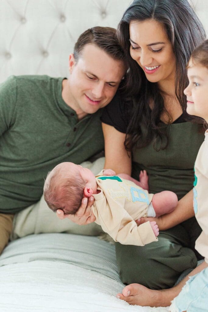 mom holding baby while both mom and dad are looking at baby