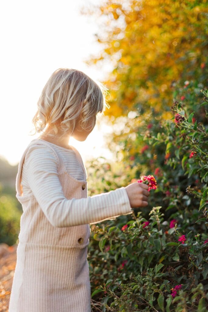 A young girl picking spring wildflowers in a Temecula park, a sweet and low-key Easter activity for families with little ones.