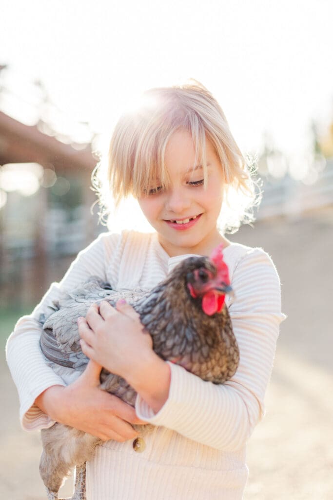 Capturing the simple, authentic beauty of childhood as a young girl hugs her pet chicken in a Murrieta backyard.