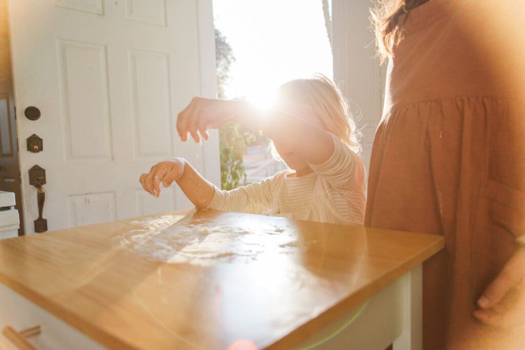Authentic lifestyle photography in Temecula of a mother and daughter baking together, capturing the beauty of a lived-in kitchen and genuine connection.